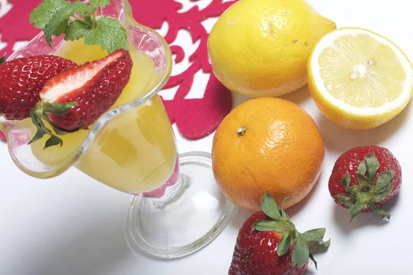 Çilek ve nane ile dekore edilmiş çanak çömlek, jöle. Yanındaki masa meyve vardır: mandalina, limon ve bayut. — Stok fotoğraf