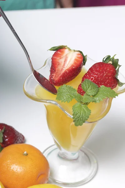 在陶器的果冻, 装饰草莓和薄荷。桌子旁边是水果: 官员, 柠檬和 bayut. — 图库照片