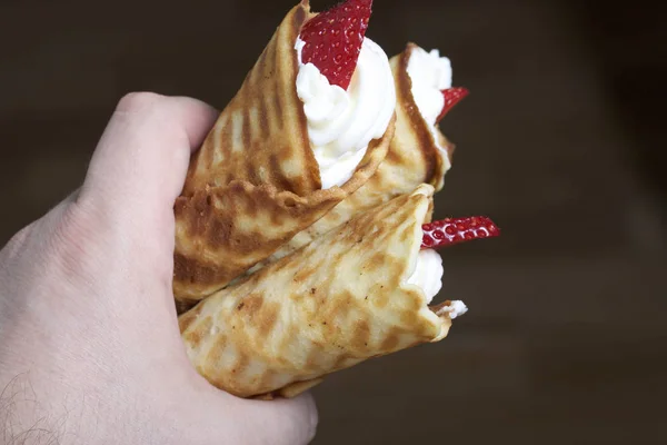 Cuernos de gofre con crema, decorados con fresas. En la mano . — Foto de Stock