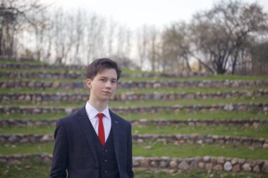 Genç bir adam, Klasik takım elbiseli bir genç. Ellerini ceplerine koyarak yaz amfitiyatro taş basamaklar üzerinde duruyor.