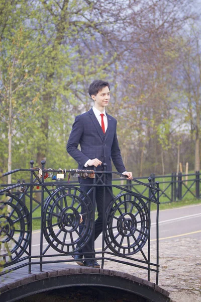 Un jeune homme, un adolescent, en costume classique. Promenade le long des avenues du parc de printemps . — Photo