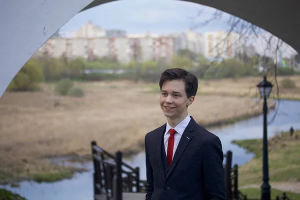 Un joven, un adolescente, con un traje clásico. Caminando por las avenidas del parque de primavera . —  Fotos de Stock