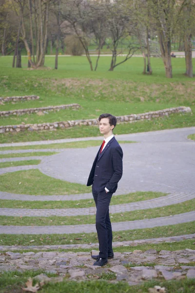 Un jeune homme, un adolescent, en costume classique. Il se tient sur les marches de pierre de l'amphithéâtre d'été, mettant ses mains dans ses poches . — Photo