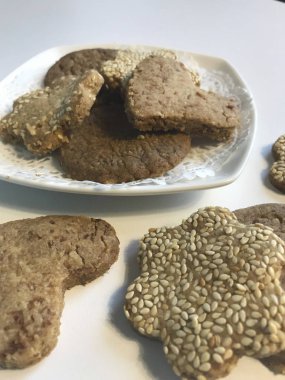 Kurabiye kurabiye ile susam bir plaka üzerinde. Beyaz masa, beyaz yemekleri. Yukarıdan görüntülemek.