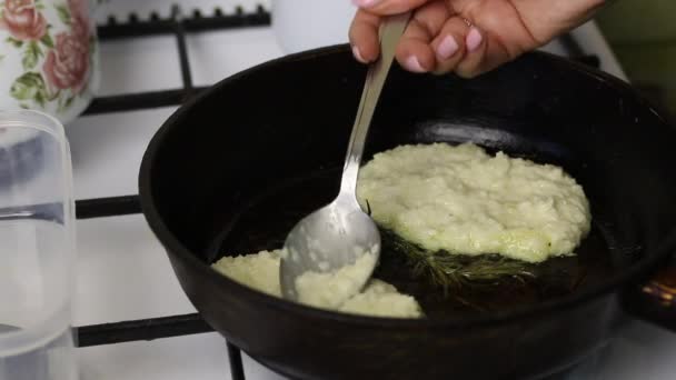 Des crêpes aux frites de femme. Une femme met de la purée de pommes de terre sur une poêle chaude. A proximité se trouve un brin de romarin — Video