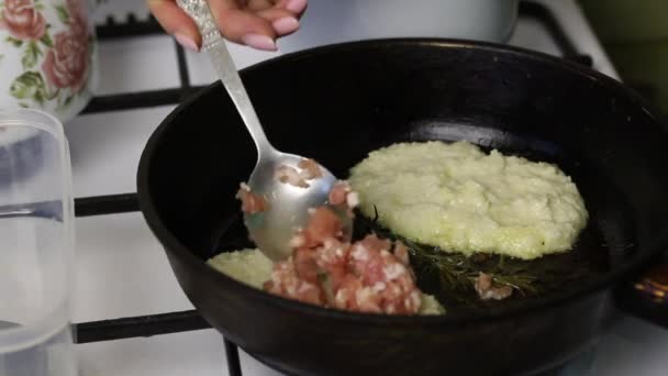 妇女薯条煎饼与切肉。 土豆泥在热油锅里. 一个女人在上面放了切碎的肉. — 图库视频影像