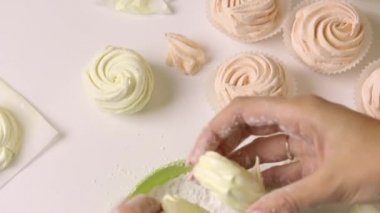 Bir kadın marşmelov hazırlıyor. Krema şekeri içinde yuvarlanıyor. Yukarıdan yakın çekim..