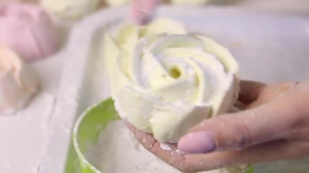 Uma mulher rola marshmallows na forma de uma rosa em açúcar de confeiteiro. Perto da superfície da mesa está um marshmallow pronto . — Vídeo de Stock