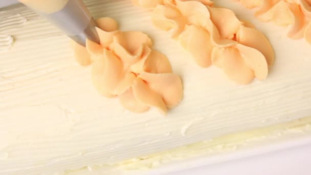 Una donna decora con crema un rotolo di biscotto ricoperto di crema. Usa una sacca da pasticceria — Video Stock