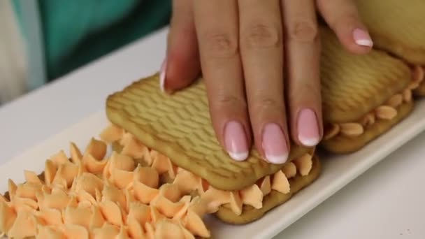 한 여성 이 과자와 크림으로 과자를 만들고 있습니다. 쿠키 위에 크림 쿠키를 덮는다. — 비디오