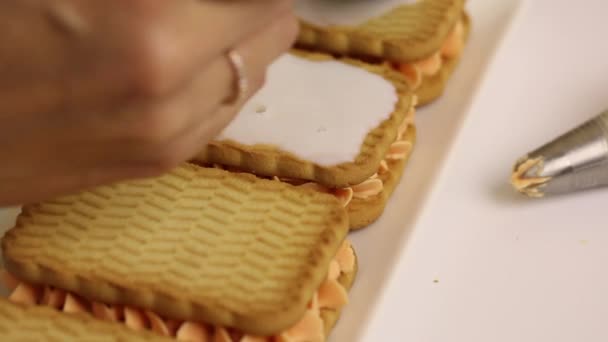 Une femme prépare des pâtisseries à partir de biscuits et de crème. Arroser les biscuits de lait pour adoucir . — Video