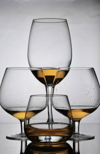 足の短いワイングラスのゴブレット。近くには長い脚のガラスとウイスキー用のガラスがあります。グラスには少量のアルコールが入っている。. — ストック写真