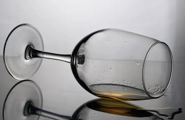 Uzun bacaklı bir şarap kadehi. Yan yatar, ışıkta fotoğraflanır. İçinde az miktarda alkol var..