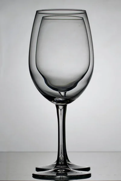 Wine glass goblets on a long leg. Two glasses to the light, one by one. — Stock Photo, Image