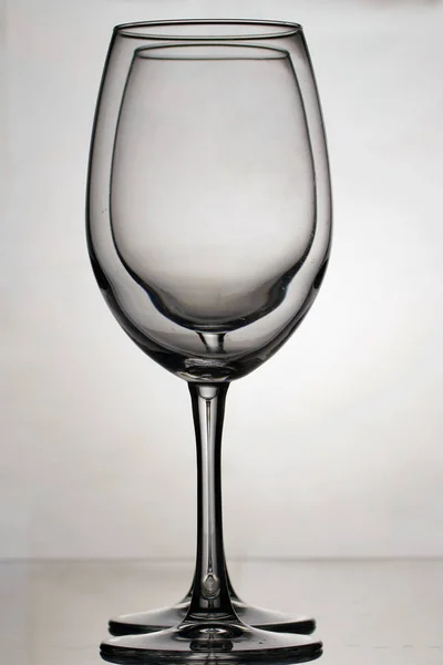 Gobelets en verre de vin sur une longue jambe. Deux verres à la lumière, un par un . — Photo
