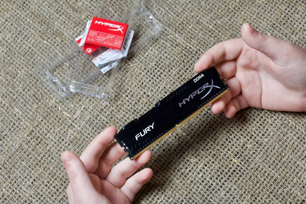 MINSK, BELARO - 25 NOVEMBRE 2019: Un uomo tiene una barra di RAM HyperX Fury 8GB DDR4. Nelle vicinanze si trova la confezione da lei . — Foto Stock