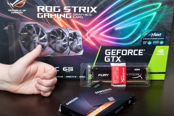 MINSK, BELARUS - 25 NOVEMBRE 2019: Un uomo sta considerando componenti per assemblare un computer da gioco. Scheda video ROG Strix GeForce GTX 1660 Ti Advanced Edition 6GB. RAM HyperX Fury 8GB DDR4 RAM. Samsu — Foto Stock