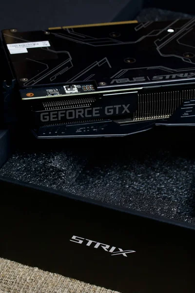 MINSK, BELARUS - 25 NOVEMBRE 2019: Un uomo apre il pacchetto con la scheda grafica ROG Strix GeForce GTX 1660 Ti Advanced Edition 6GB. La marcatura del dispositivo è visibile . — Foto Stock