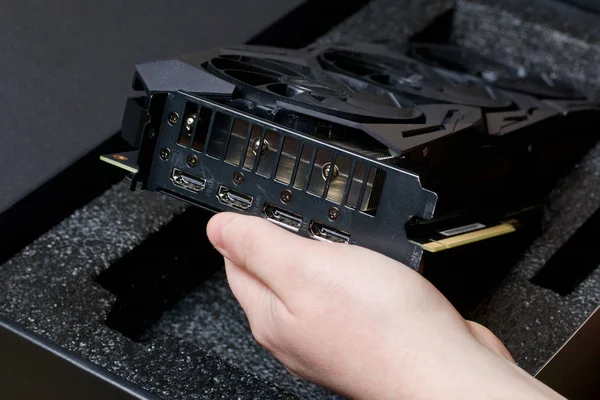 MINSK, BELARUS - 25 NOVEMBRE 2019: Un uomo apre il pacchetto con la scheda grafica ROG Strix GeForce GTX 1660 Ti Advanced Edition 6GB. È possibile vedere i refrigeratori del dispositivo . — Foto Stock