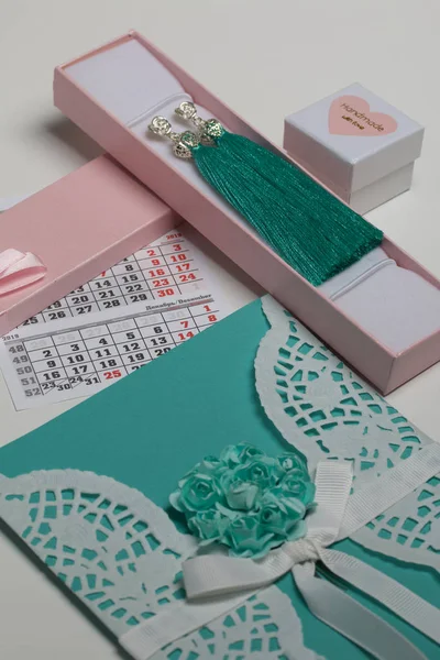 Tarjetas de felicitación y regalos en cajas artesanales. Pendientes de borla hechos a mano. Cerca hay un fragmento del calendario con el mes de diciembre . — Foto de Stock