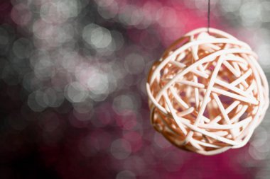 Rattan topları iplikte asılı duruyor. Pembe-gri renkli Bokeh 'in arka planına karşı.