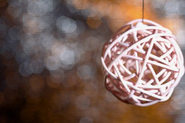 Rattan topları iplikte asılı duruyor. Sarı-gri renkli Bokeh 'in arka planına karşı.