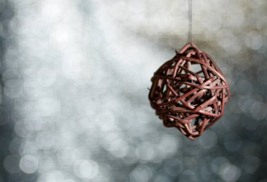 Rattan topları iplikte asılı duruyor. Beyaz-gri renkli bir bokeh arkaplan karşısında.