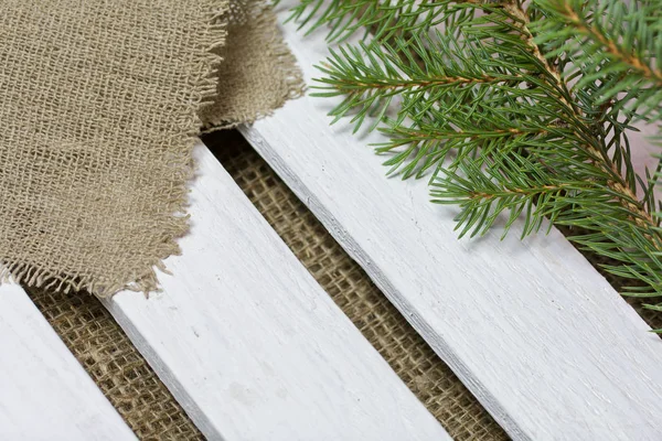 Fir branch and linen fabric on the background of wooden boards. The boards are painted white. — Stock Photo, Image