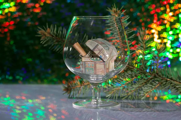 Otevřená truhla s dárky a vzkazem složeným do trubice. Stojí ve sklenici vína. Na pozadí jedlové větve a duhového bokeh. — Stock fotografie