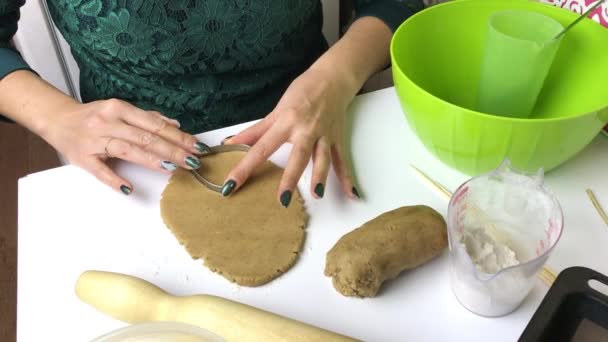 Kvinna förbereder pepparkakor. I en valsad deg klämmer den ihop kakorna med hjälp av en form. Skjuten ovanifrån. — Stockvideo