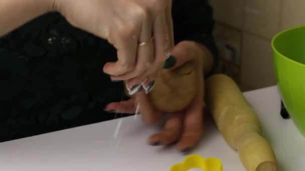 A nő mézeskalács sütit készít. A kezével gyúrja a tésztát, és egy sodrófával gurítja..