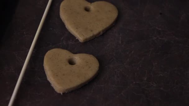 Cucinare biscotti allo zenzero. Pezzi di pasta a forma di cuore che giacciono su una teglia . — Video Stock