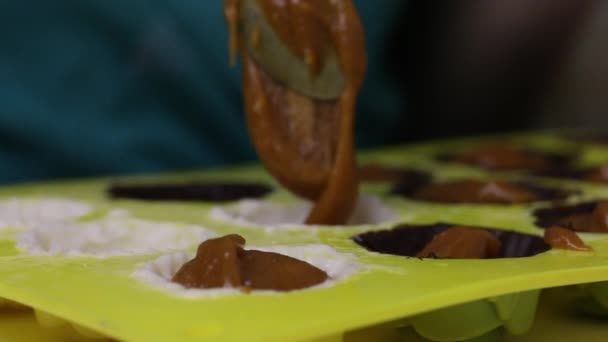 Femme met un remplissage pour les bonbons glacés. Pose dans un moule en silicone, huilé avec du chocolat liquide 