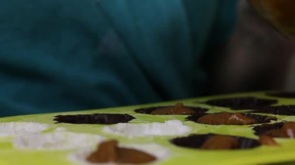 La donna mette un ripieno per caramelle glassate. Stende in uno stampo di silicone, oliato con cioccolato liquido . — Video Stock