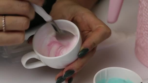 Eine Frau macht farbige Zuckerguss, um Ingwerplätzchen zu dekorieren. vermischt Glasur mit rotem Farbstoff. — Stockvideo