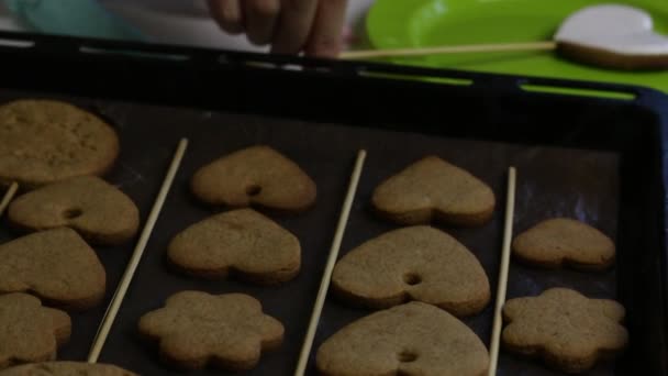 Hartvormig peperkoekje met suikerglazuur. Taartzakjes met gekleurd glazuur. In de buurt op een bakplaat zijn koekjes voor decoratie. — Stockvideo