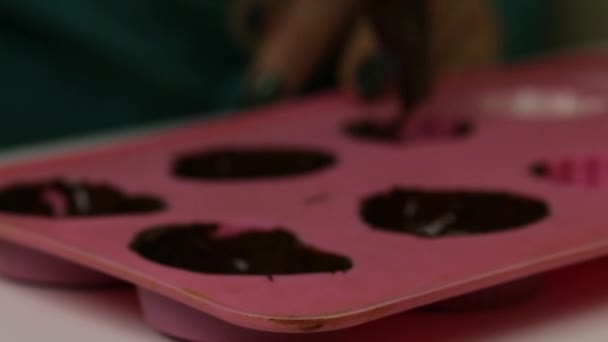 Uma mulher lubrifica um molde de silicone com chocolate líquido. Para a preparação de doces envidraçados. Imagem de close-up . — Vídeo de Stock