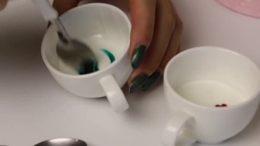 Bir kadın zencefilli kurabiye süslemek için renkli şeker kreması yapıyor. Cilalamayı yeşil boyayla karıştırır.