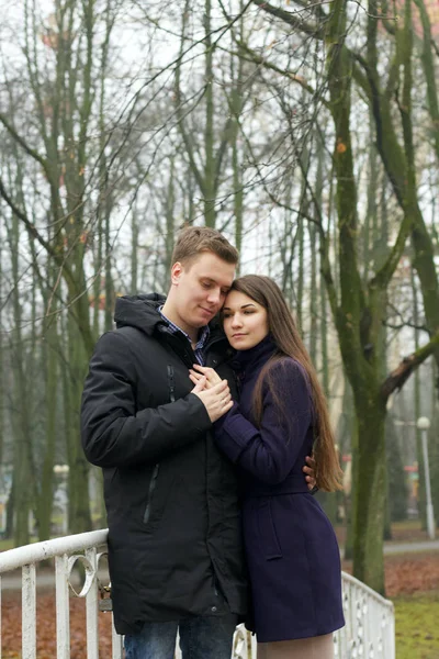 Unga par poserar nära räcket på en fotbro i parken. Sen höst, dimma. — Stockfoto