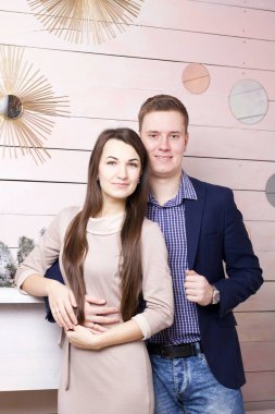 Dekoratif şöminenin yanında poz veren neşeli karı koca. Şenlikli kıyafetler ve dekorasyonlar..