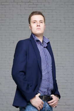 Kibirli bir ifadeyle genç bir adam. Ellerin ceplerinde dikiliyorsun.