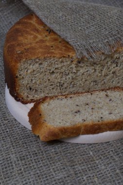 Taze pişmiş ekmek. Bir somun ekmek kesilir ve kesme tahtasının üzerinde yatar. Yüzey ketenle kaplı..