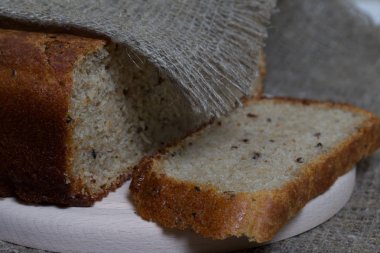 Taze pişmiş ekmek. Bir somun ekmek kesilir ve kesme tahtasının üzerinde yatar. Yüzey ketenle kaplı..