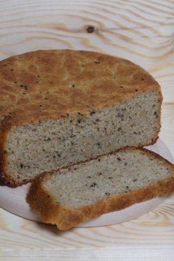 Taze pişmiş ekmek. Bir somun ekmek kesilir ve kesme tahtasının üzerinde yatar. Çam ağacından arkaplan.