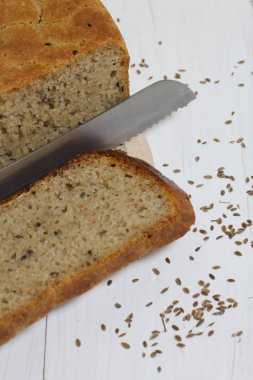 Taze pişmiş ekmek. Bir somun ekmek kesilir ve kesme tahtasının üzerinde yatar. Dill tohumları etrafa saçılmış ve bir bıçak var..