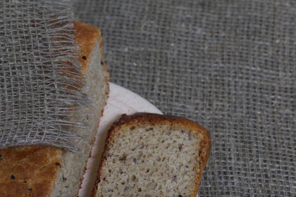 Pane appena sfornato. Una pagnotta di pane viene tagliata e giace su un tagliere. La superficie è coperta di lino . — Foto Stock