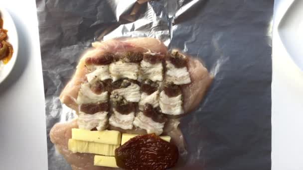 Un hombre pone manteca de cerdo, queso, salami y tomates secados al sol en el pollo. Hace que el rollo . — Vídeos de Stock