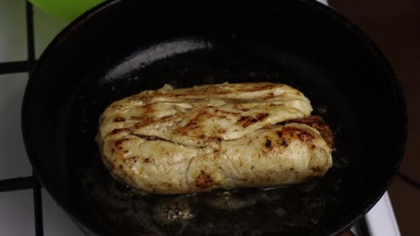 Em uma frigideira aquecida na manteiga, o rolo de filé de frango é frito. Um homem segura um rolo com garfos. Você pode ver como o óleo ferve e uma crosta dourada aparece .. — Vídeo de Stock