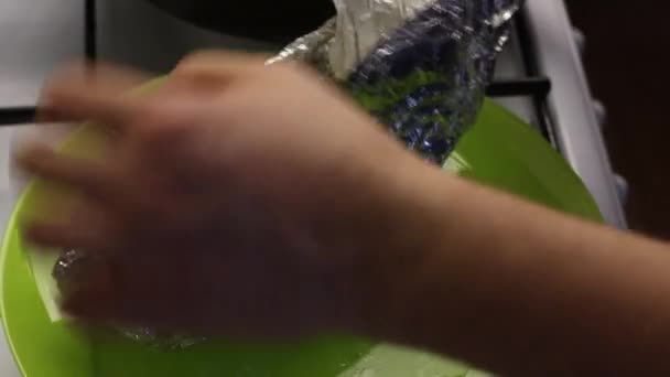 En man tar bort folie från en bakad kycklingfilé. Använder en plugg. Fyllningen av rullen är synlig, ånga kommer från den. — Stockvideo