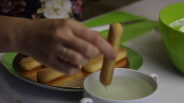 Eine Frau backt einen Kuchen aus savoyardi-Keksen. Kekse in Sirup tauchen und auf ein Substrat legen — Stockvideo